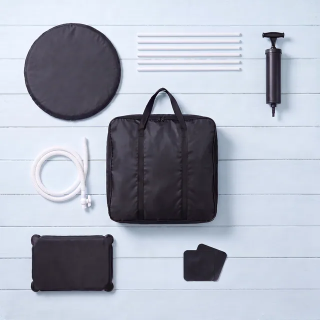 Top-down view of the Ice Bath Tub kit on pale blue boards: the round padded lid, six white support tubes, the black hand pump, the white drain hose with its valve, the black carry bag holding the folded tub, the black water cushion and two black repair patches