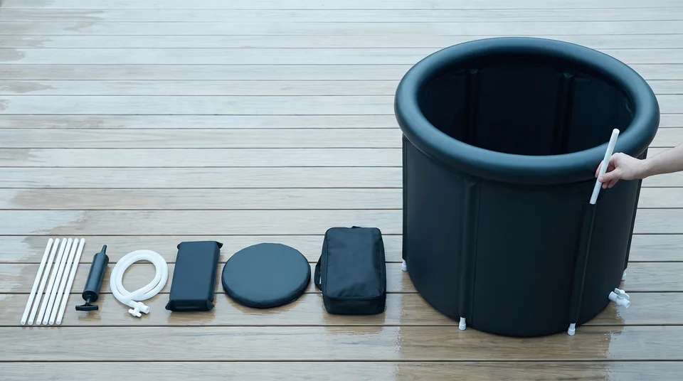 A hand sliding the last support tube into the Ice Bath Tub on light deck boards, with the kit parts laid out in a row